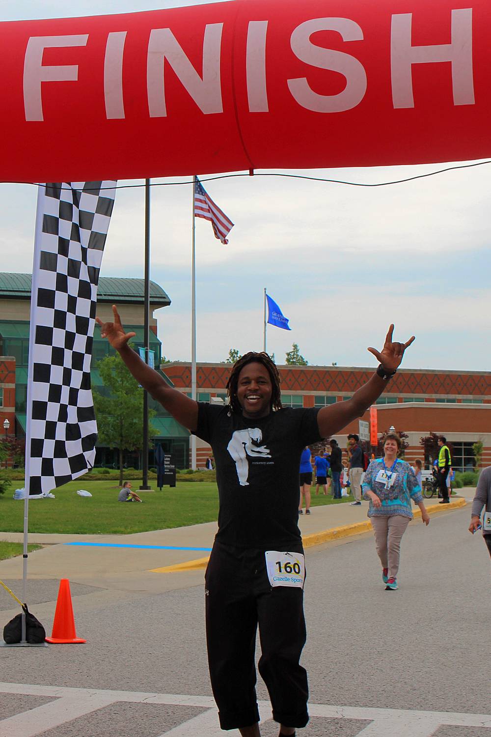 Torrey Thomas holding his hands high in the air, smiling wide, as he crosses the finish line